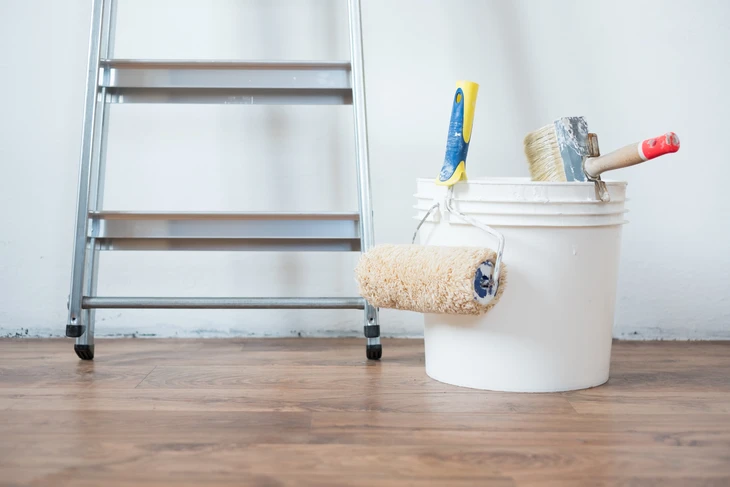 Plombier en intervention dans une cuisine moderne, portant une ceinture à outils équipée et tenant des flexibles d'alimentation colorés