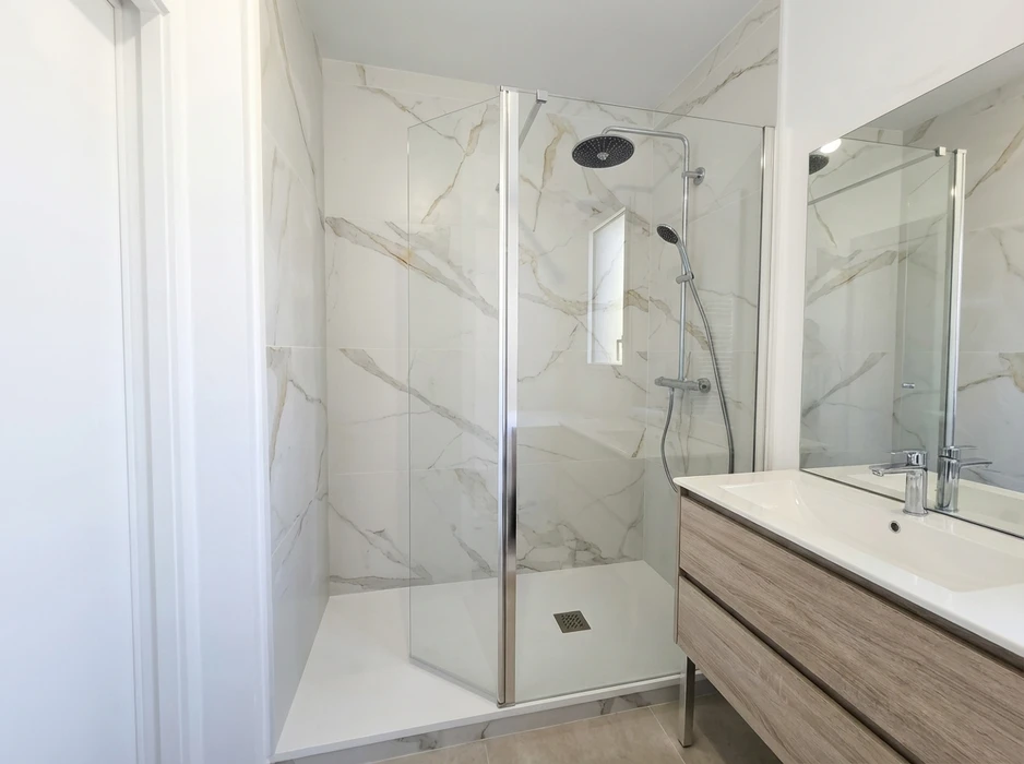 Salle de bain moderne avec douche à l'italienne encadrée de parois en verre trempé à profils chromés