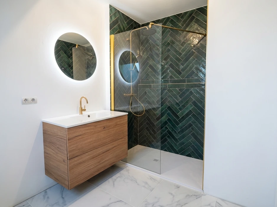 Salle de bain moderne avec douche à l'italienne carrelée en zellige vert foncé disposé en chevrons, robinetterie et profilés en laiton brossé doré