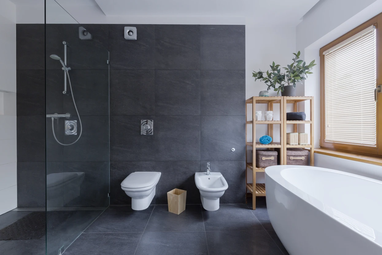 Salle de bain moderne avec douche à l'italienne, WC suspendu et bidet contre mur en carrelage anthracite