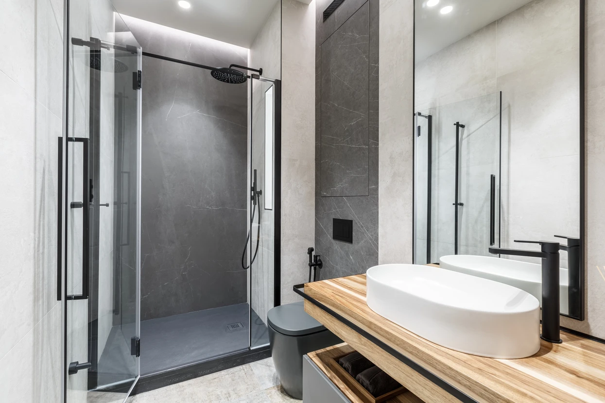 Salle de bain moderne avec douche à l'italienne, vasque ronde blanche sur plan de travail en bois, robinetterie noire mate