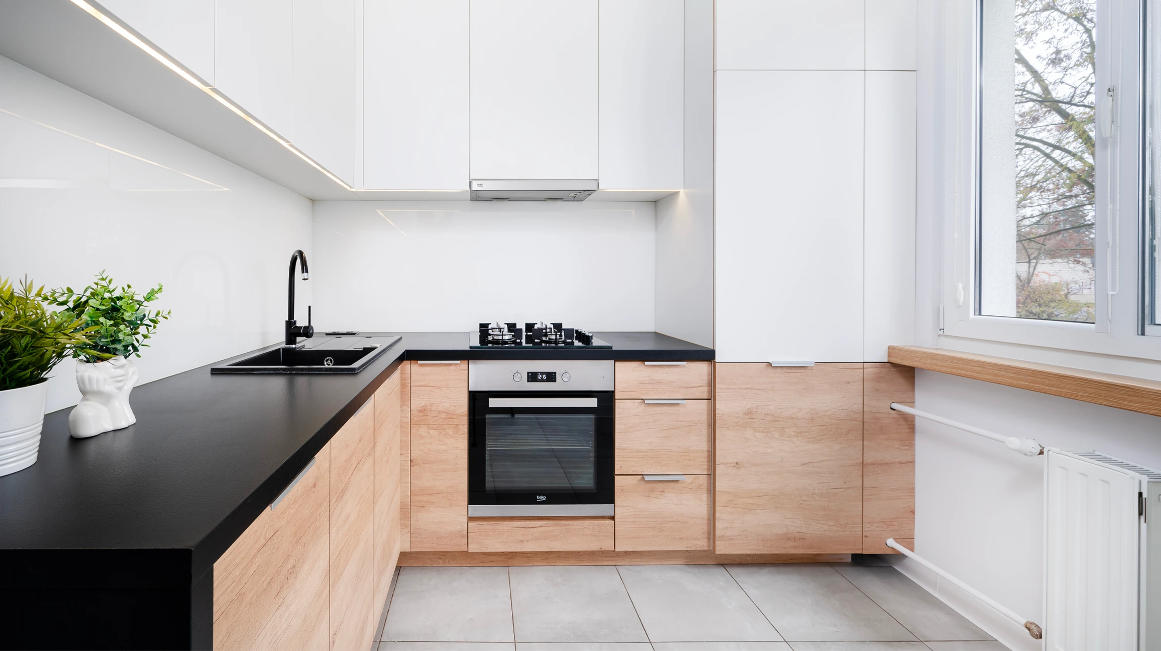 Cuisine moderne avec installateur professionnel en uniforme rouge montant un tiroir blanc dans meuble bas gris anthracite
